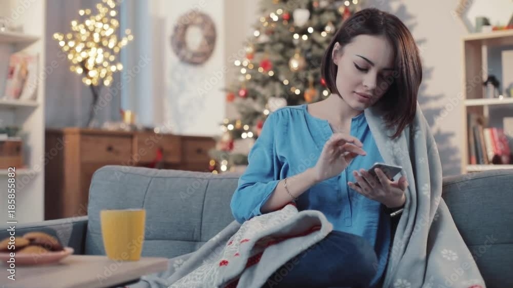 Young serious attractive woman drinks tea use pnone sit on the sofa in home background christmas tree brunette girl home mobile internet cell cellphone communication online slow motion Young serious attractive woman drinks tea use pnone sit on the sofa in home background christmas tree brunette girl home mobile internet cell cellphone communication online slow motion