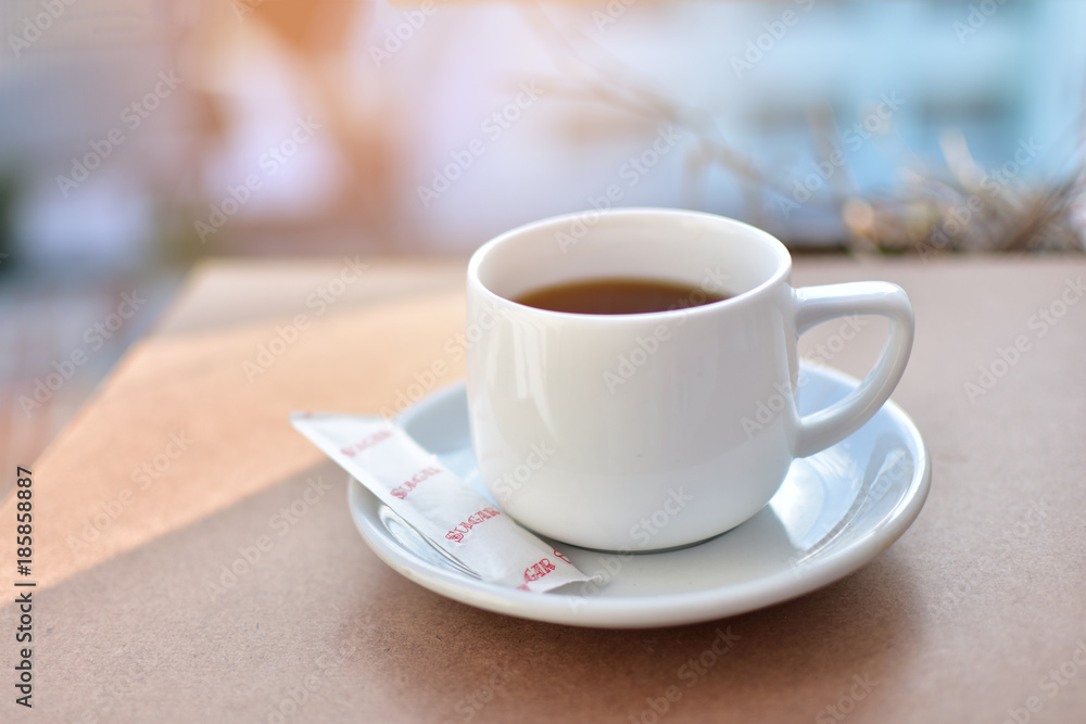 cup of coffee at morning on wooden table. subject is blurred.