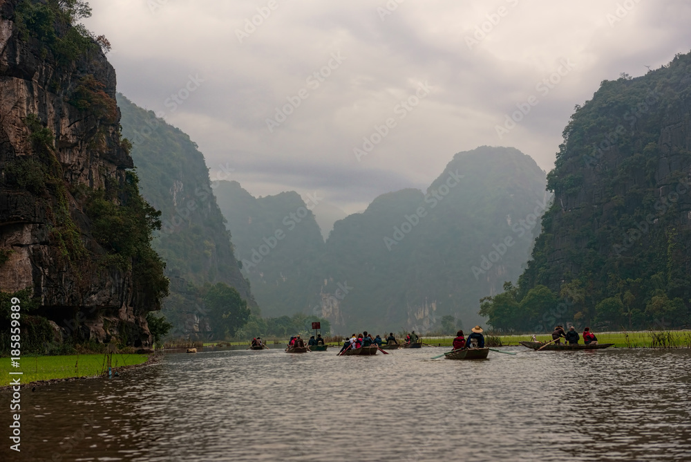 Row boats on a river under cast sky in Vietnam