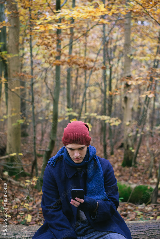 Man using phone on trunk in forest Man using phone on trunk in forest