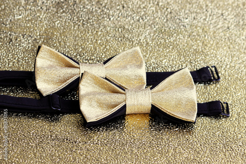 Two festive golden with a black bow tie on a gold background. photo