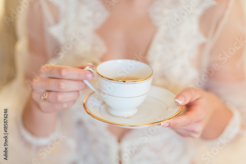 Cup of tea or coffee in female hands close up at morning