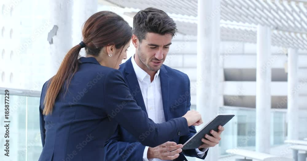 Business people discuss on digital tablet computer outside office