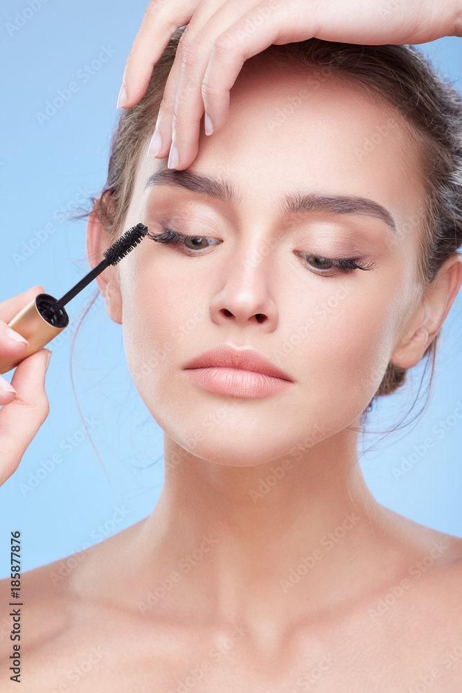 Girl painting lashes with mascara Girl painting lashes with mascara