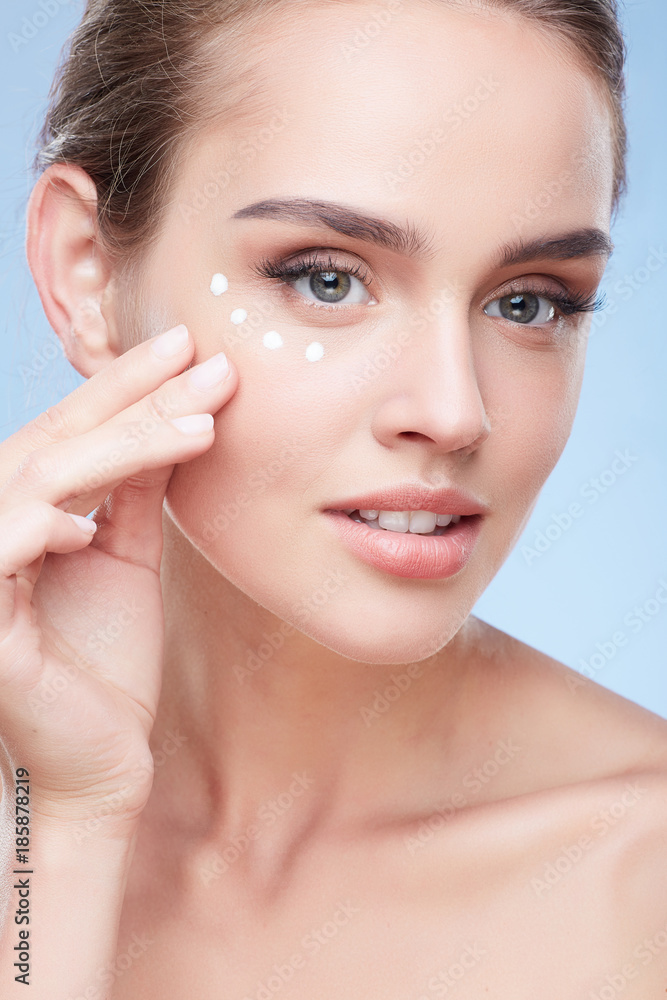 Woman applying cream under eyes