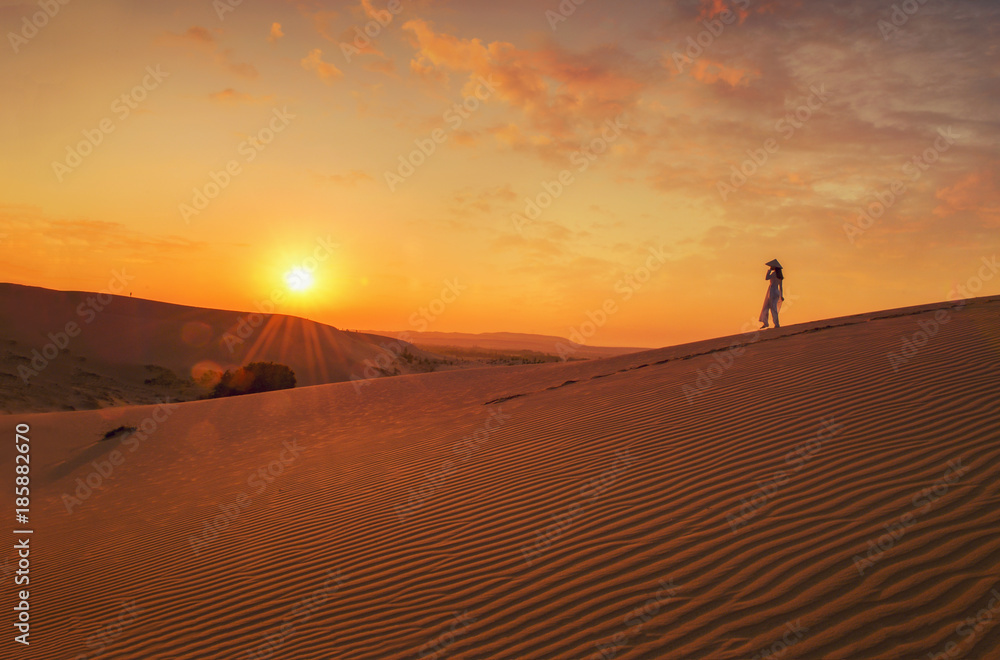 woman with Vietnam culture traditional dress on sandune during sunset ,traditional costume ,Muine Vietnam