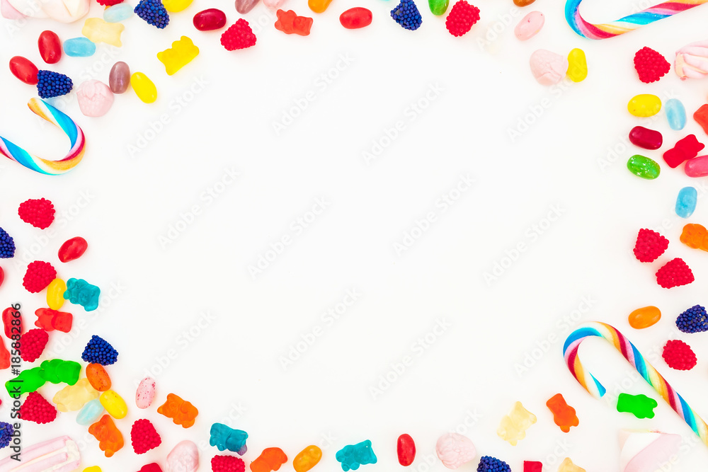 Frame made of bright candy, marmalade and candy canes on white background. Flat lay, top view. Unhealthy food