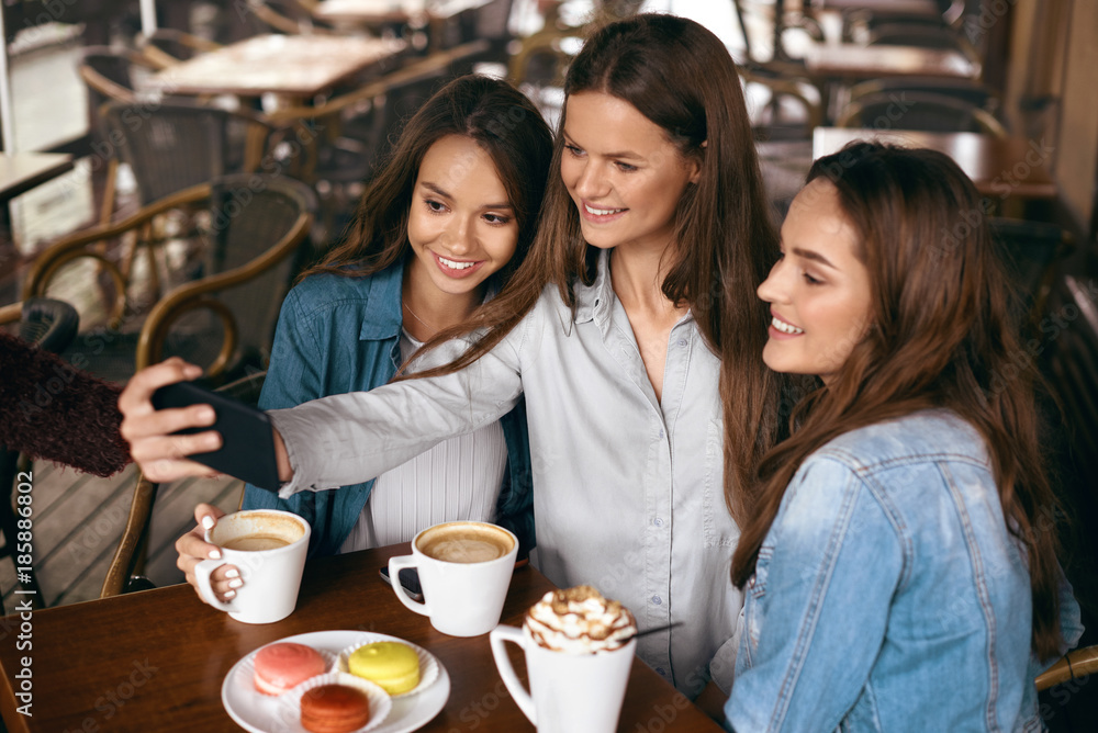 Beautiful Girls In Cafe Taking Selfie Photo On Phone. Beautiful Girls In Cafe Taking Selfie Photo On Phone.