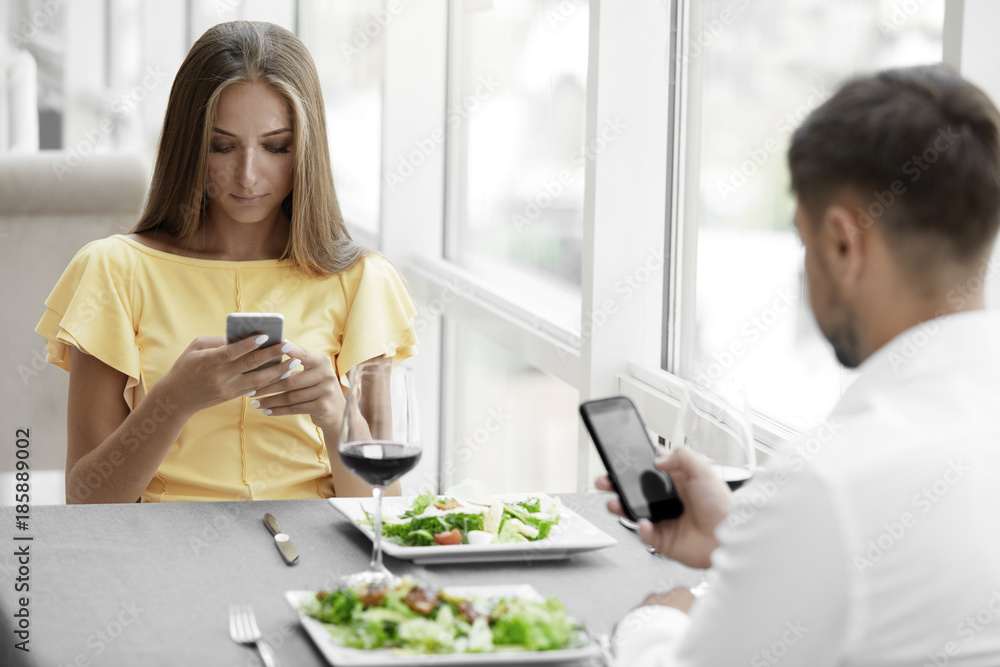 Communication Problem. Man And Woman With Phones On Date Communication Problem. Man And Woman With Phones On Date