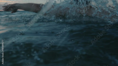 slow motion of professional swimmer swimming outdoor at sea on sunset.