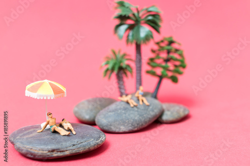 Miniature people wearing swimsuit relaxing on the rock with pink background   Valentine s day concept