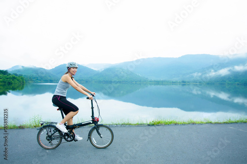 Young women riding the bicycle on the lakeside