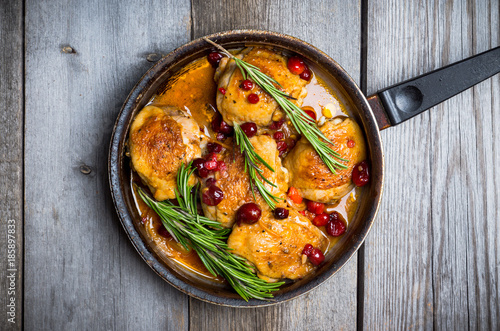 Roasted christmas chicken in a pan with cranberry and rosemary. Selective focus. Shallow depth of field.