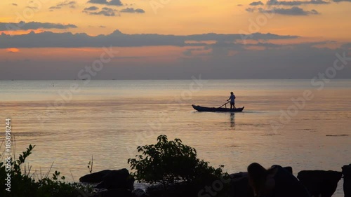 Boat on open sea sunset horizon. Silhouette at sunset. View from the coast