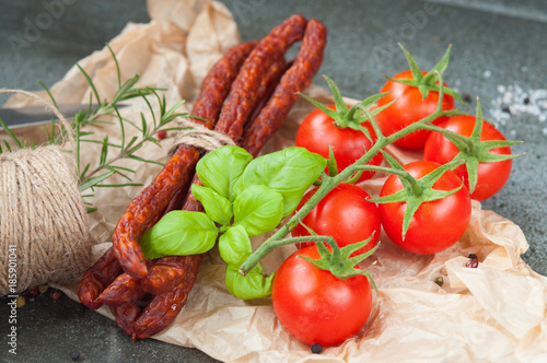 pork sausages and cherry tomatoes on a stone table