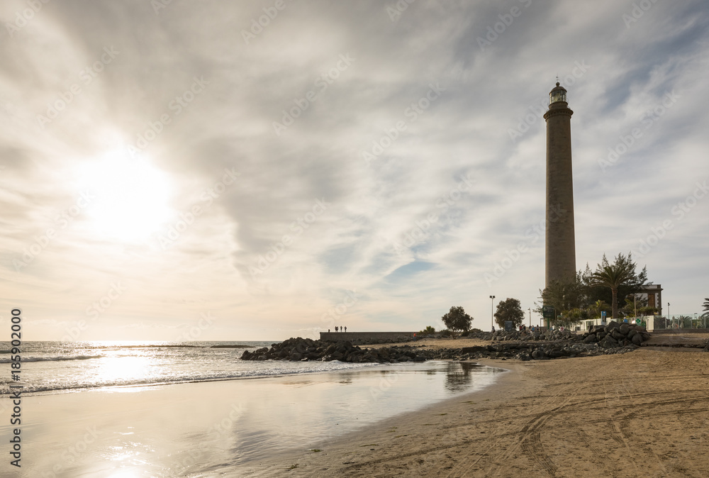 Horizontal shot of the beautiful beach in Maspalomas, with Faro de Maspalomas or Maspalomas lighthouse, in the background, Gran Canaria, Spain