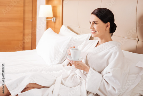 Daily routine. Confident inspired happy woman lying in profile carrying cup and thinking about day plan