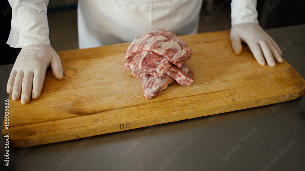 Closeup of professional chef prepare meat ribs on cutting board at restaurant kitchen