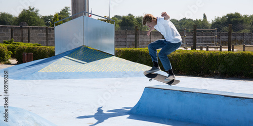 Skateboarder jump in the street from below teenager boy shate park photo