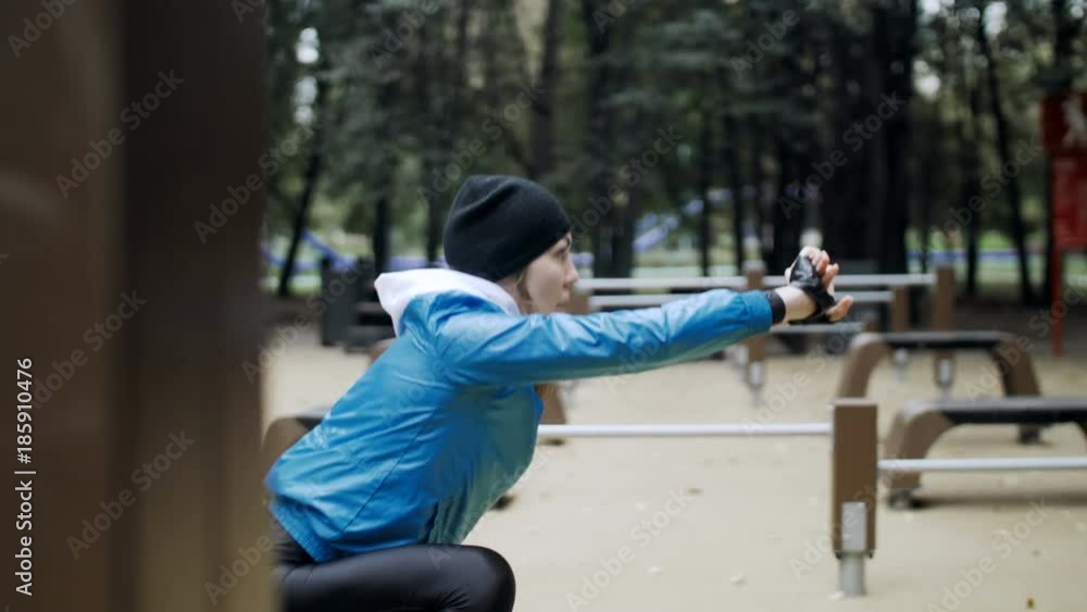 Fitness woman stretching legs with lunge hamstring stretch exercise leg stretches, doing workout in the park. Athlete in training clothes do exercises. Healthy lifestyle. Shooting from behind pillar Fitness woman stretching legs with lunge hamstring stretch exercise leg stretches, doing workout in the park. Athlete in training clothes do exercises. Healthy lifestyle. Shooting from behind pillar
