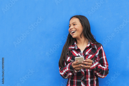 Portrait of beautiful latino girl using the mobile in the street. photo