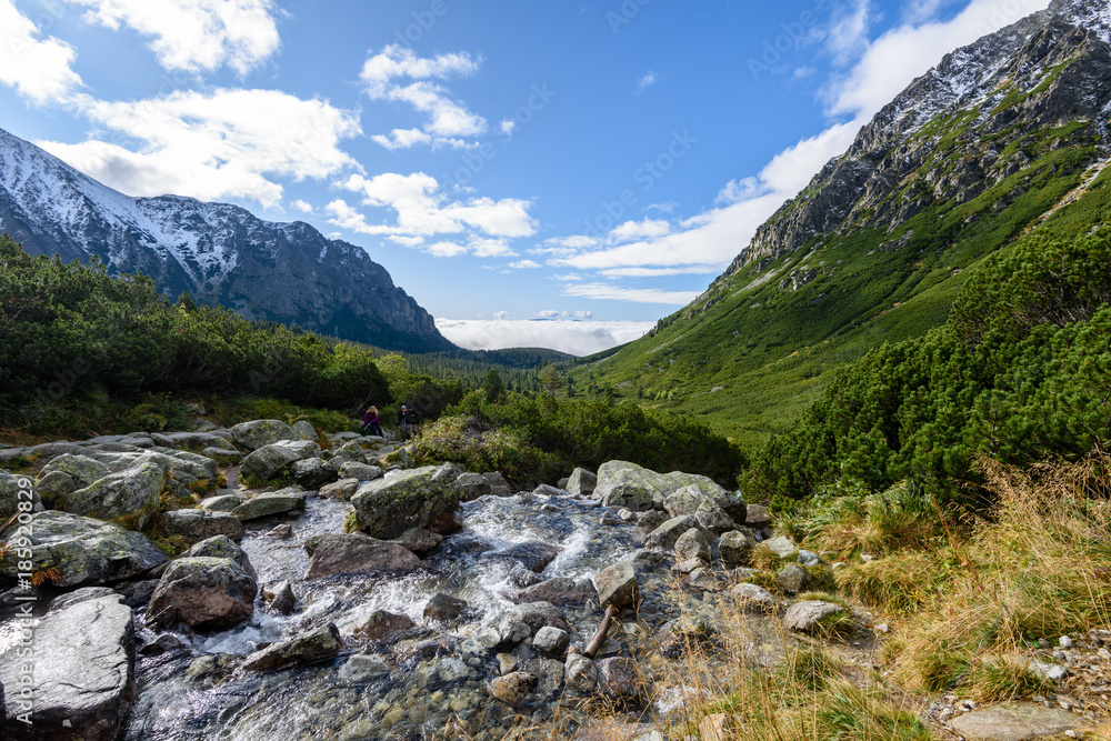 large Waterfall from ravine in autumn, long exposure with mountains in background