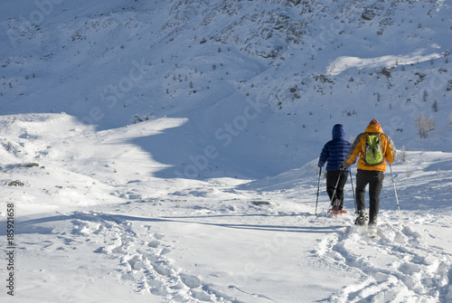 man and woman, sporty, walking with snowshoes in fresh snow, high mountains, sunny and cold day, following path, head towards the Breithorn peak, rock, winter, Alps, Valais, Simplon Pass, Switzerland