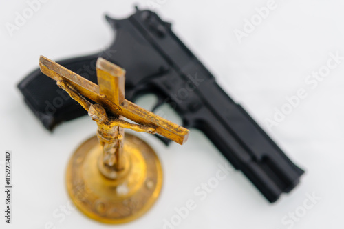 Foto Handgun beside an old brass crucifix