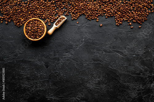 Coffee background. Roasted beans in bowl and scoop on black table top view copyspace