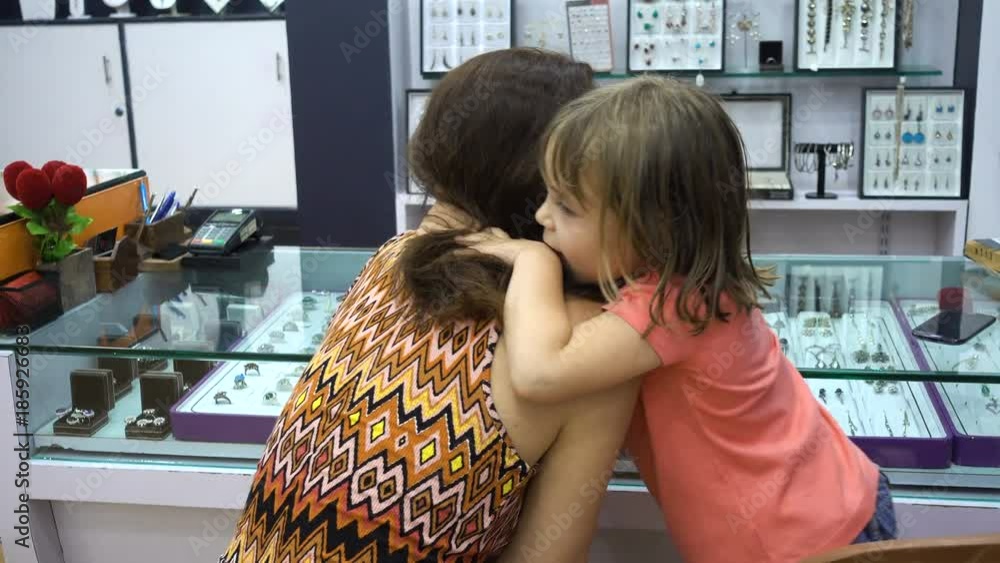 Mom and daughter in a jewelry store. The girl is 4-5 years old. They choose jewelry. A woman of European or American appearance. In front of them is a showcase with jewelery stones. India, Goa. Mom and daughter in a jewelry store. The girl is 4-5 years old. They choose jewelry. A woman of European or American appearance. In front of them is a showcase with jewelery stones. India, Goa.