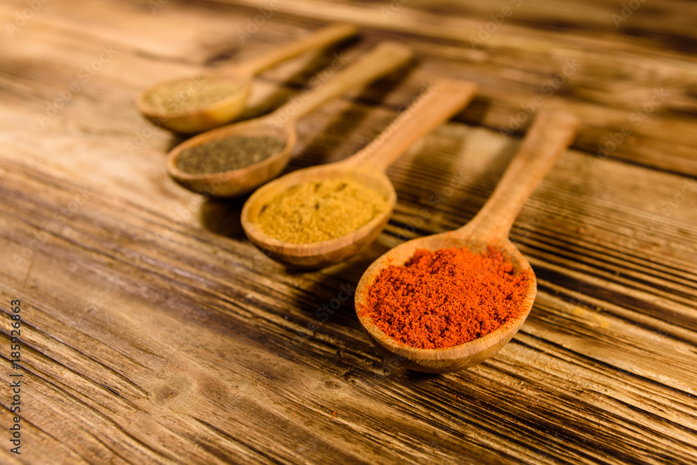 Spoons with the different spices on wooden table Spoons with the different spices on wooden table