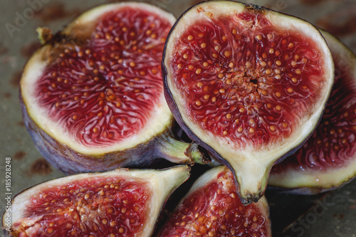 Sweet red ripe figs on a bunch of lies on a beautiful metal stand .