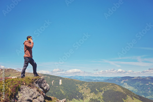 Tourist a taking selfie on peak above mountain valley with sunrise and fog