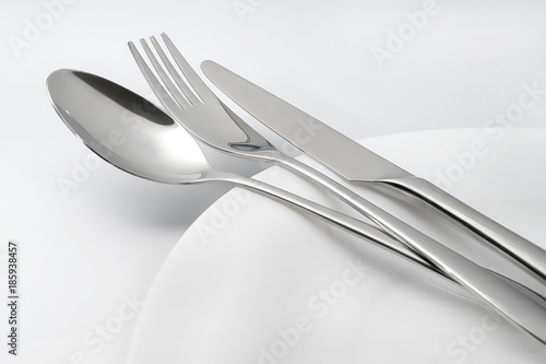 Spoon, fork and knife on white empty plate