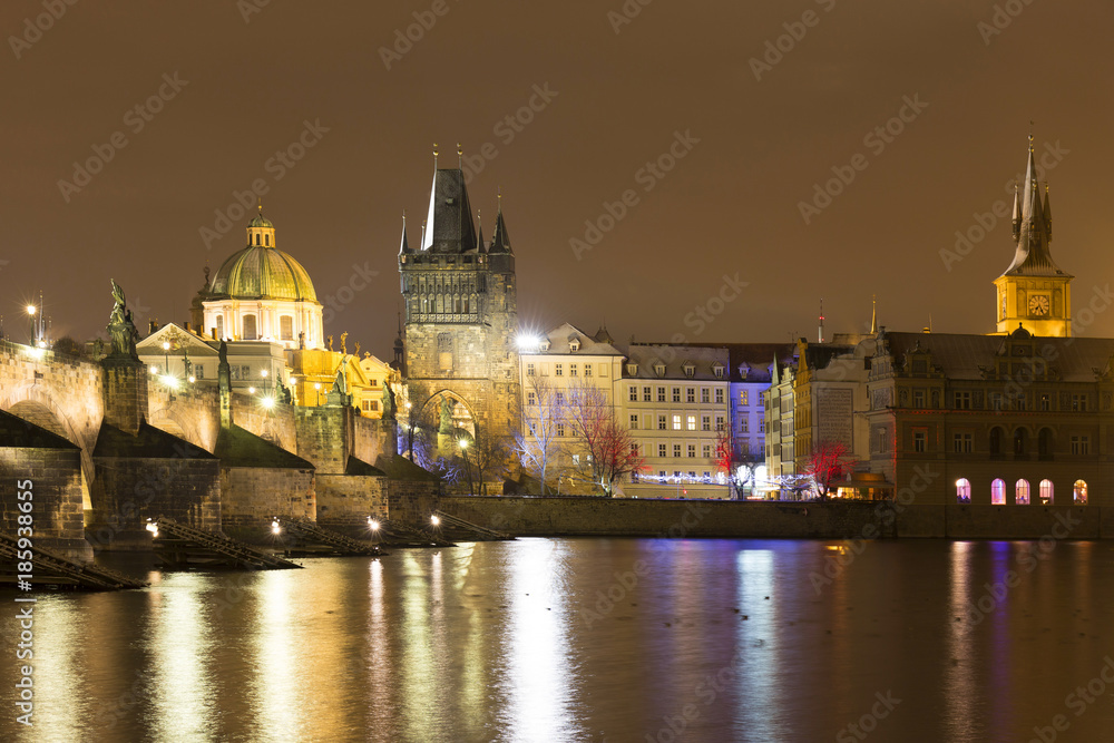 Fototapeta premium Night snowy Prague Old Town with Bridge Tower and St. Francis of Assisi Cathedral and Charles Bridge with its baroque Statues, Czech republic