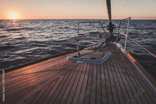 Tableau sur toile sunset on wooden sailing yacht's bow on open sea panorama