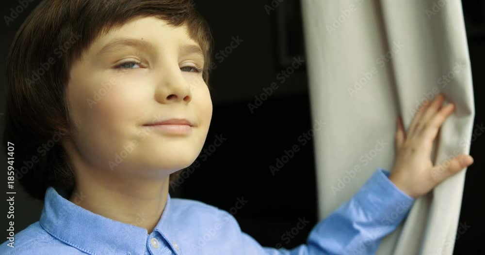 Portrait of little boy coming to the window, opening the curtain at looking outside. Close up. Portrait of little boy coming to the window, opening the curtain at looking outside. Close up.