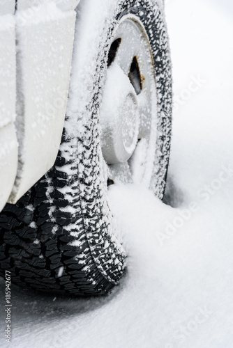 Close up detail of a snow buildup on a tire while parked in a snow storm, vertical image
