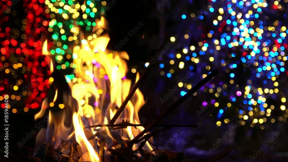 Fire burning with Christmas light bokeh in the background during the holidays. Fire burning with Christmas light bokeh in the background during the holidays.