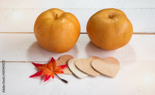 Close up the Chinese pear put on timber board in front of maple leaf and wooden heart,blurry light around. photo