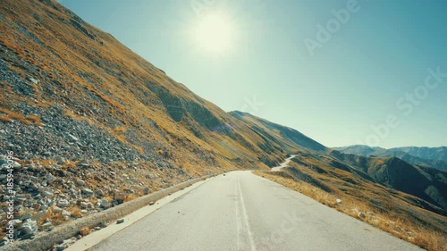 Pov drive on the winding roads of an Alpian mountain landscape on a sunny bright autumn day with the sun in view  photo