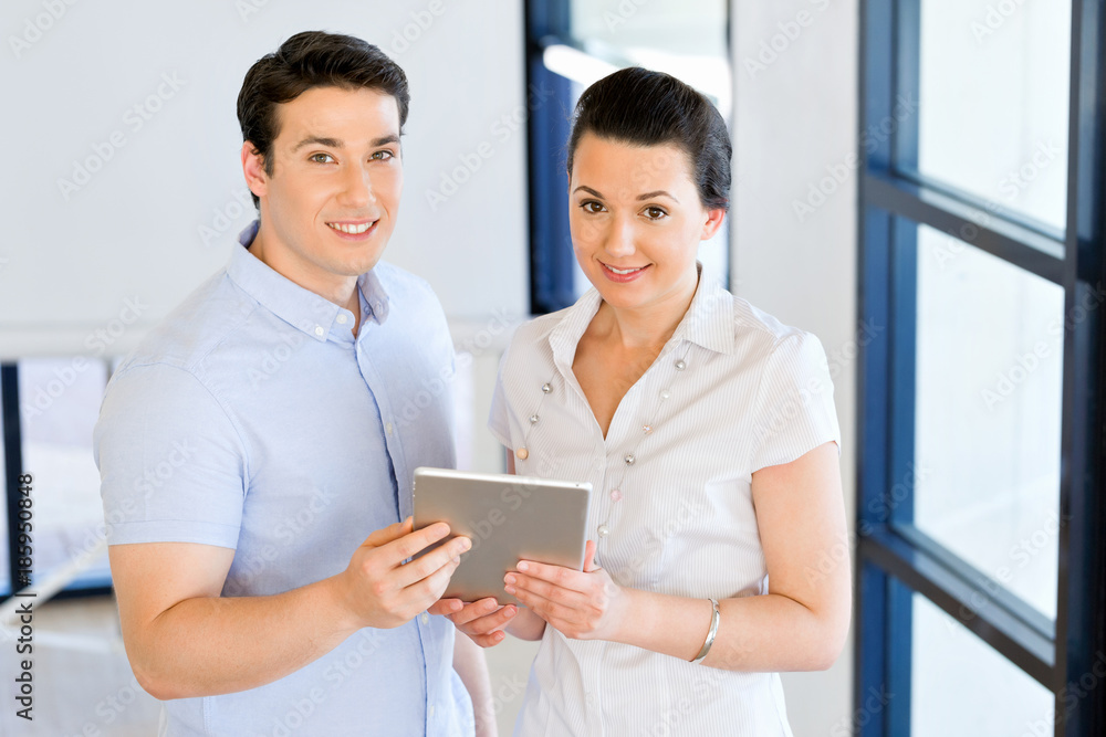 Young man and woman with touchpad standing in office Young man and woman with touchpad standing in office