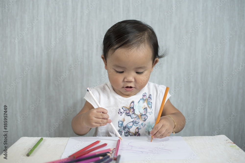 asian toddler / baby girl is having fun learning to use pencils. Education concept. human growth concept. asian toddler / baby girl is having fun learning to use pencils. Education concept. human growth concept.