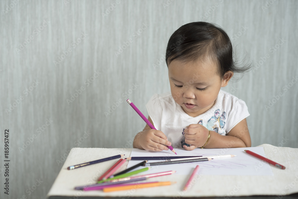 asian toddler / baby girl is having fun learning to use pencils. Education concept. human growth concept. asian toddler / baby girl is having fun learning to use pencils. Education concept. human growth concept.