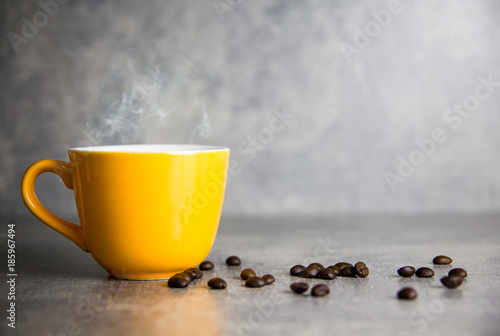 yellow cup of coffee and coffee bean with concrete background