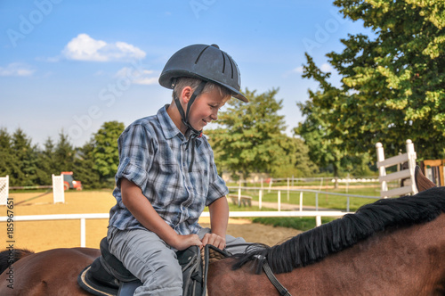 ein 9 jähriger Junge reitet allein auf dem Reitpaltz auf einem braunem Pferd
