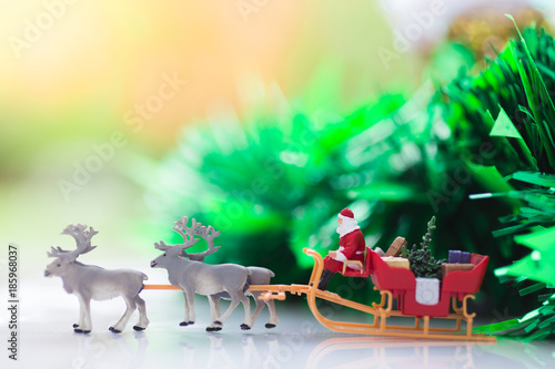 Miniature Santa Claus drive a wagon with a reindeer during the snowfall. Using as concept in Christmas day. © polymanu