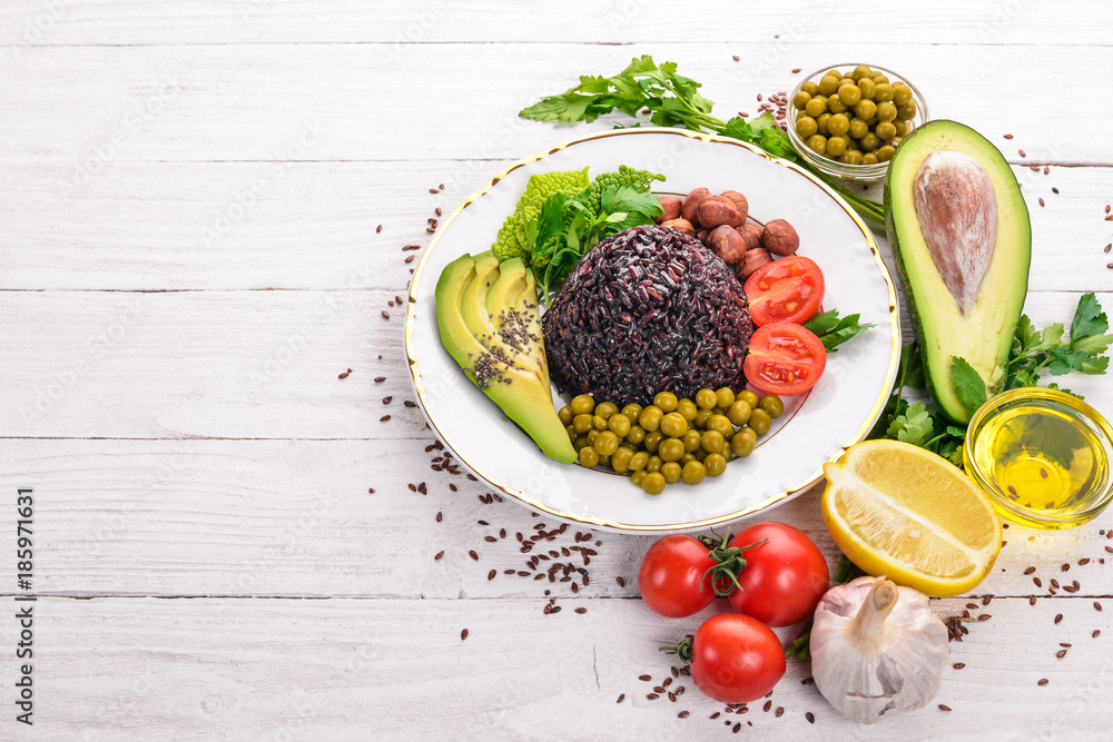 Healthy food. Black rice, avocado, cherry tomatoes, green peas and hazelnut. On a wooden background. Top view. Free space for your text. Healthy food. Black rice, avocado, cherry tomatoes, green peas and hazelnut. On a wooden background. Top view. Free space for your text.