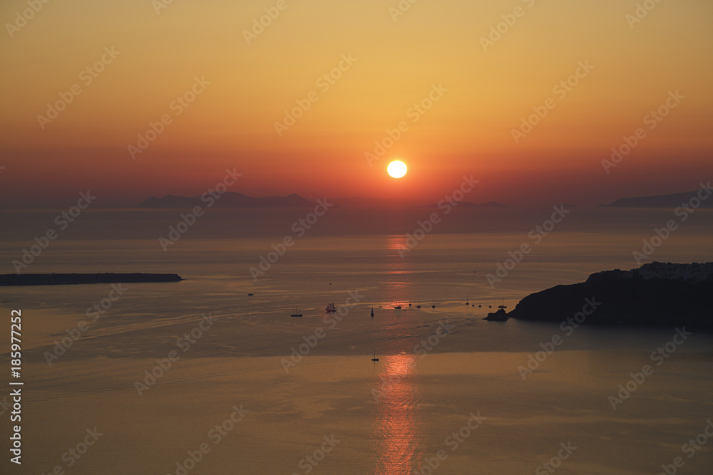 Sunset on Santorini island with some sailboats, Greece