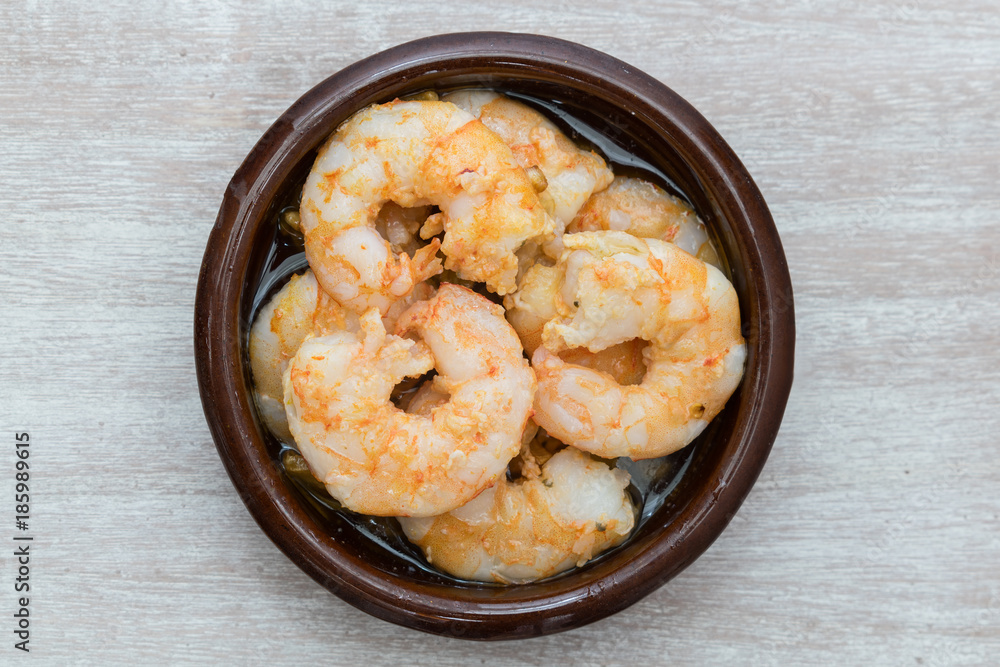 Prawns with garlic. Popular dish of Spanish cuisine. The ingredients are peeled prawns, garlic and olive oil. Served in clay pot They must be eaten quickly, without getting them to cool down. Prawns with garlic. Popular dish of Spanish cuisine. The ingredients are peeled prawns, garlic and olive oil. Served in clay pot They must be eaten quickly, without getting them to cool down.